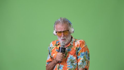 Handsome senior bearded tourist man ready for vacation against green background