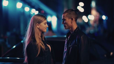 Close up portrait of beautiful young couple kissing at night city street at colorful lights background. Love story, romantic atmosphere, true feelings. Happy together.