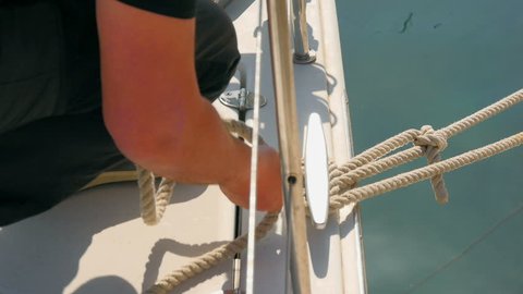 Sailor unties rope before sailing boat departs from concrete pier. Filmed on sailing trip in Croatia on Adriatic sea.