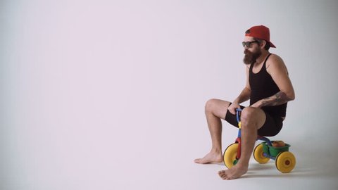 A funny bearded man is riding a children's bicycle.