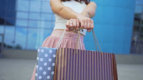 Active attractive girl dances near a shopping center with full of purchases shopping bags