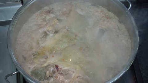 traditional beef broth with vegetable, bones and ingredients in pot, cooking recipe. Soup in a cooking pot with ladle on dark stone background. Top view 