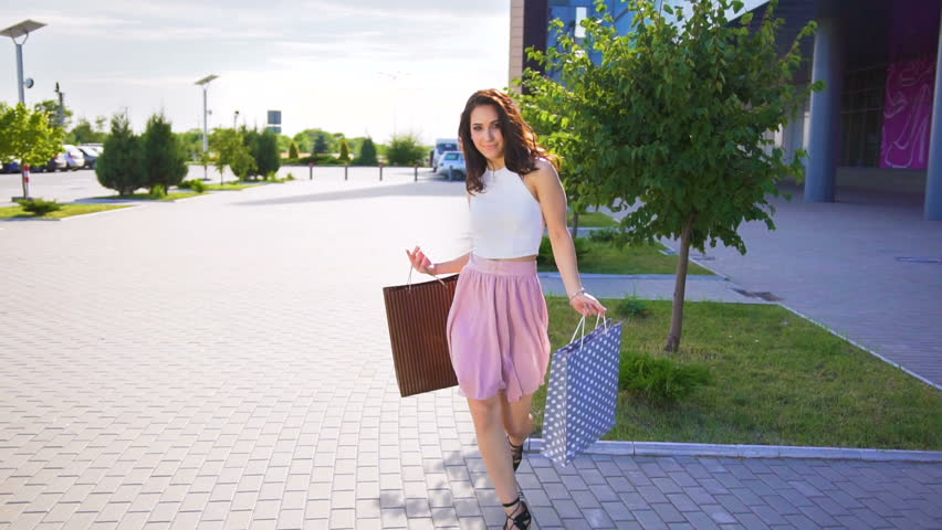 Happy woman holding shopping bags and dancing after shopping near mall Royalty-Free Stock Footage #1012210916