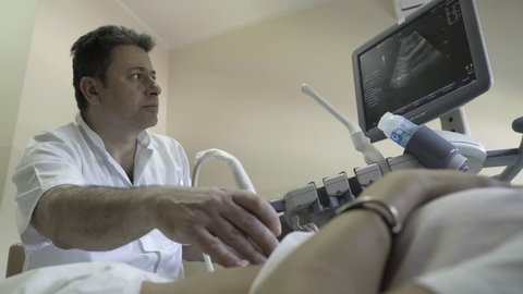 Doctor gynecologist performing examination with ultrasound on gynecology ward in hospital, woman on medical review, hand close up, low angle view, female patient lying in ambulance room, health care