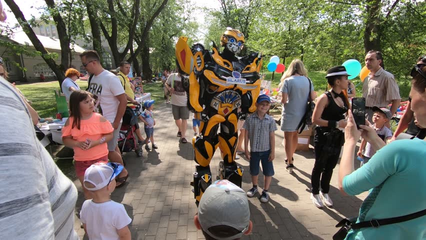Minsk, Belarus, June 3, 2018: Animator in a suit of robot transformer among children in a city park.