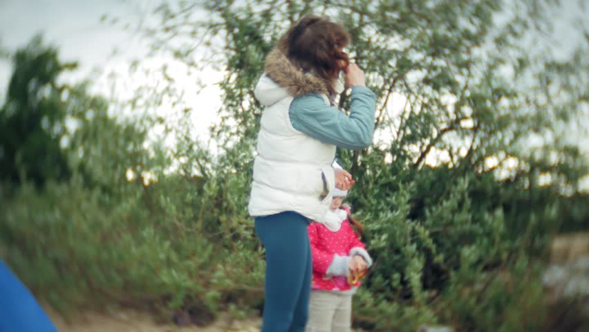 Happy and beautiful mother and daughter are feeding gulls on the beach on the river bank 4k
