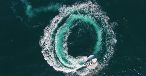 Upper view white motorboat sails making foamy circles on deep blue sea surface