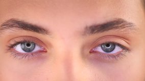 Beautiful human eyes close-up. Young Woman Blue eyes Macro Closeup blinking and looking at camera. 4K UHD video