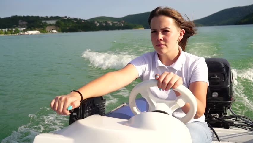 The Young Girl Steers The Motor Boat On The Lake