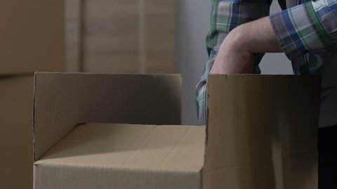 Man packing stuff into carton, divorce, division of property, moving from house