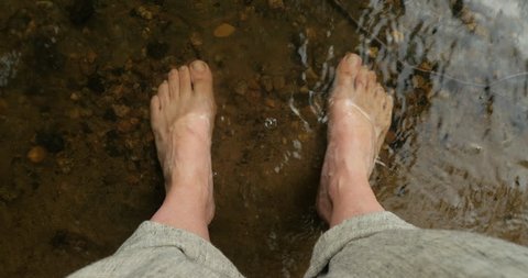 Woman resting her bare feet in a cool mountain stream, river, or lake