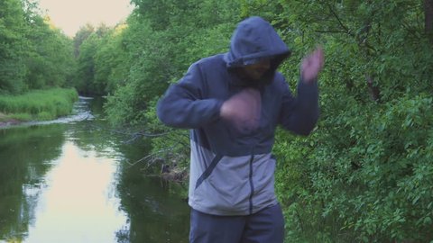 Mosquitoes and beetles attack a young man near the river. A man is waving his hands desperately.