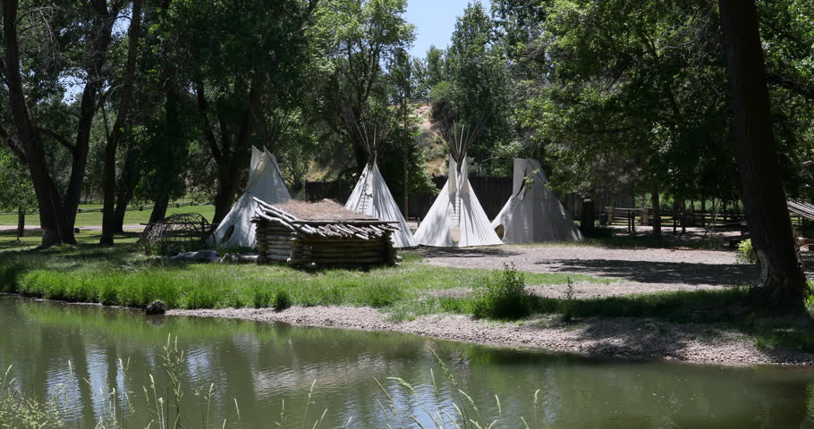 Rendezvous Indian camp along river lake. Fort Buenaventura in Ogden, Utah reproduction of pioneer, trader, hunter and native American Indian teepee camp.