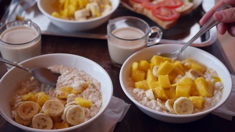 Delicious breakfast on vacation, stir in a plate of mango, banana and oatmeal. close-up. HD, 1920x1080, slow motion