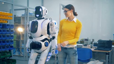 Young woman is slapping a human-like robot after it spanks her playfully