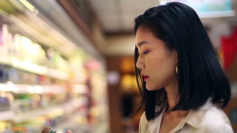 asian woman looking at groceries good at super market deciding what to buy.