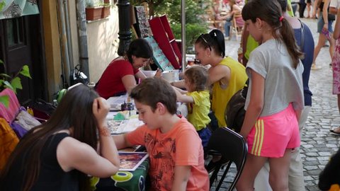 Plovdiv, Bulgaria, June 2018 - Artist applying henna tattoo on children during street festival