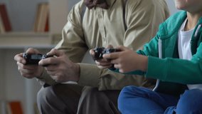 Excited school boy competing in video game with grandfather, family closeness