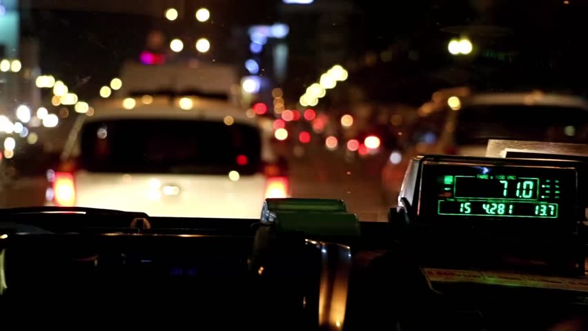 The digital taxi meter on the dashboard of cab shows kilometer and cost. Night taxi ride in traffic jam. Royalty-Free Stock Footage #1012259183