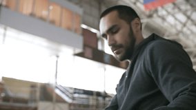 Tilt up with PAN of confident sportsman with prosthetic leg sitting down on bench in indoor stadium and opening gym bag with sportswear - Powered by Shutterstock - Get 15% off with code: PIKWIZARD15