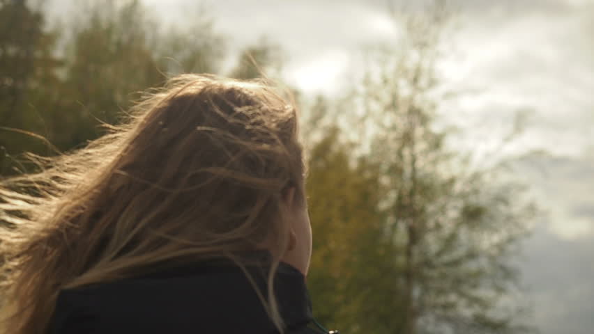 Wind flutters young girls hair.  Young girl walking looking something in the distance with wind in her hair.  Young girl hair is blowing in the wind 