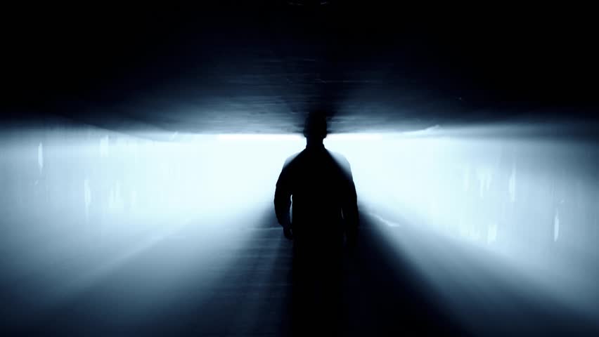 Silhouette of person walking in tunnel to the bright light. Royalty-Free Stock Footage #1012280129