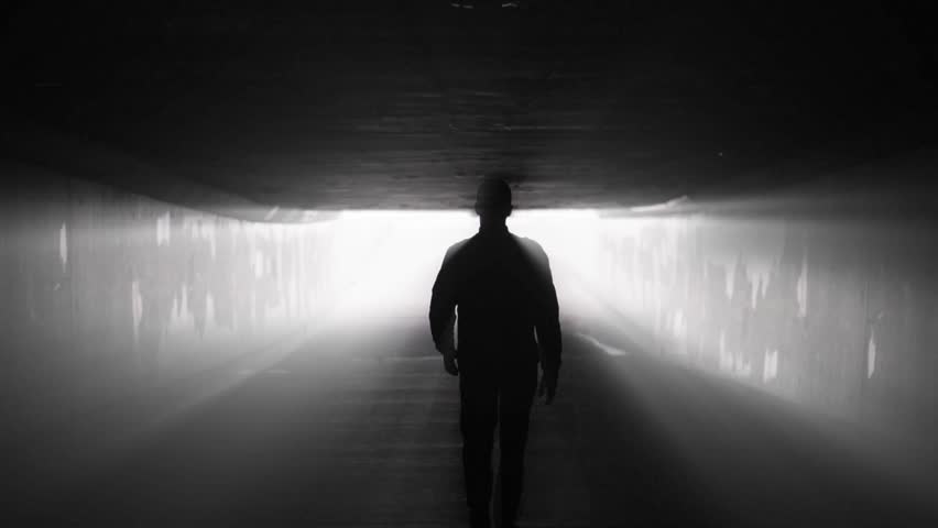 Silhouette of man walking in tunnel to the light. Concept of afterlife Royalty-Free Stock Footage #1012280132