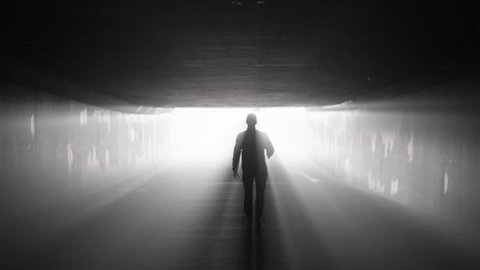 Silhouette of man walking in tunnel to the light. Concept of afterlife