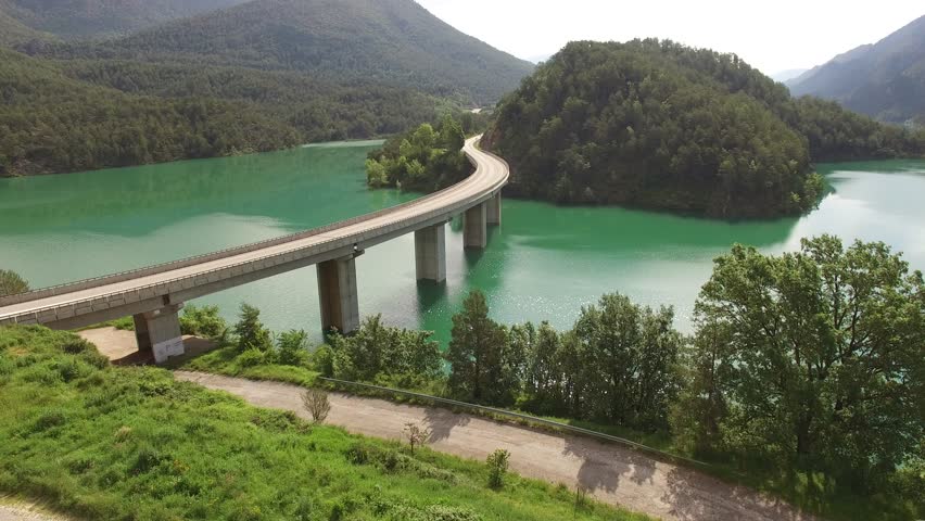 Aerial viewof bridge road curve on lake. Calm, laminated and reflective mirror water. Location, The Llosa del Cavall, c462 road, near Barcelona. Lleida Pyrenees Mountains, Catalonia, Europe