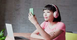 woman sit on chair and use phone listen music happily at home