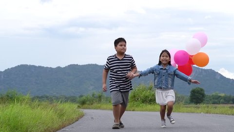 Children with balloons running slow motion on the road