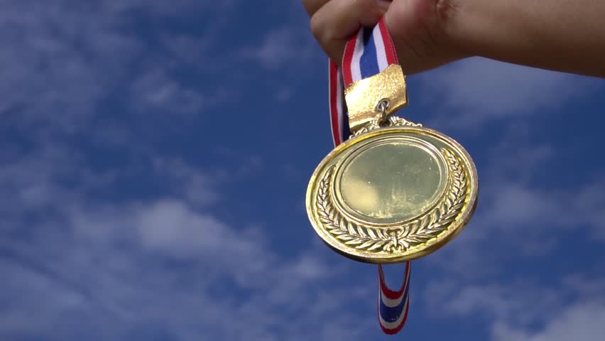 Winners Champion in success award concept : Businessman hands raised holding gold medals with ribbon against blue sky background to show success in sport or business, Slow motion video | Shutterstock HD Video #1012294097