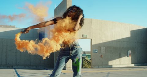 Young woman dancing outside with smoke grenade at sunset on rooftop parking garage 