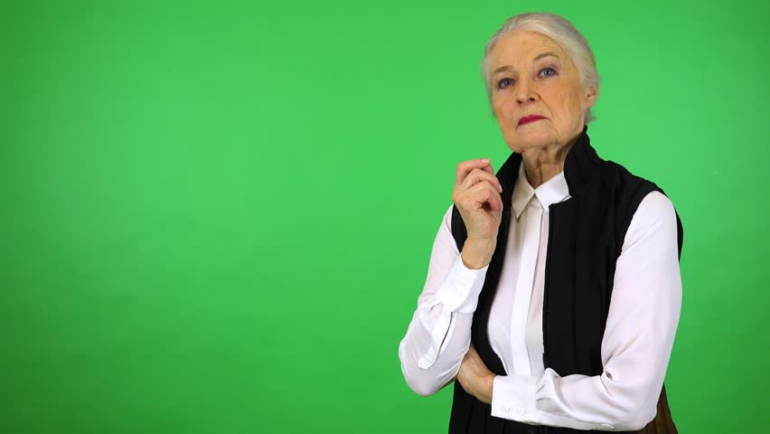 An elderly woman looks seriously at the camera - green screen studio Royalty-Free Stock Footage #1012299947