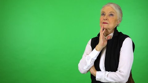 An elderly woman thinks about something - green screen studio