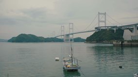 Ferry floating on water at Pier with Long Bridge across between Island, Inland sea, Japan    