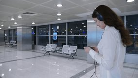 Woman watch movie on smartphone while walking at airport passage, half length tracking shot. Modern interior of international terminal sterile area, passenger spend time with film on mobile device
