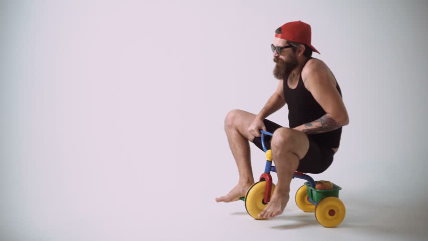 A funny bearded man is riding a children's bicycle. | Shutterstock HD Video #1012311128