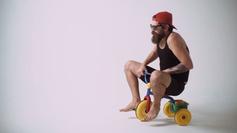 A funny bearded man is riding a children's bicycle.