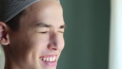 Young arabian man smiles. Eid al-Fitr. Young muslim man with prayer cap smiling