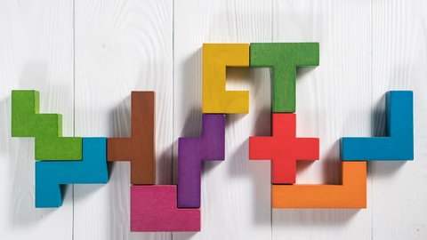 Close-up of colorful wooden blocks folding on the white table background. The concept of logical thinking. Creative background. Colorful wooden blocks moving, stop motion, animation.