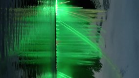 Amazing fantastic colorful fountain with bright illumination on the water pond or river with beautiful reflection at the evening or night. Beauty urban recreational concept. Vertical format video.