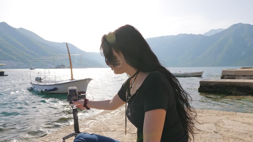 A young woman makes selfie from the phone on the stabilizer.