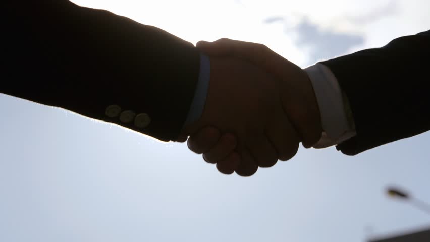 Handshake against the sun of two businessmen. Colleagues shake hands in the rays of the sun to the light | Shutterstock HD Video #1012326074