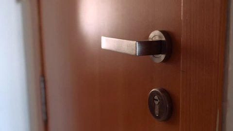 Close-up of male hands turning the key to lock the home door. Security concept.