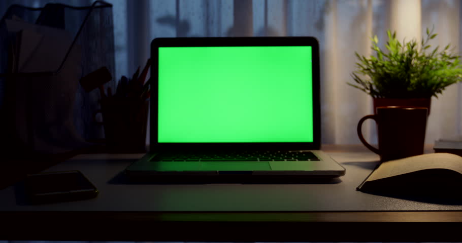 Laptop with green screen. Dark office. Dolly in. Perfect to put your own image or video.Green screen of technology being used. Chroma Key laptop Royalty-Free Stock Footage #1012335224