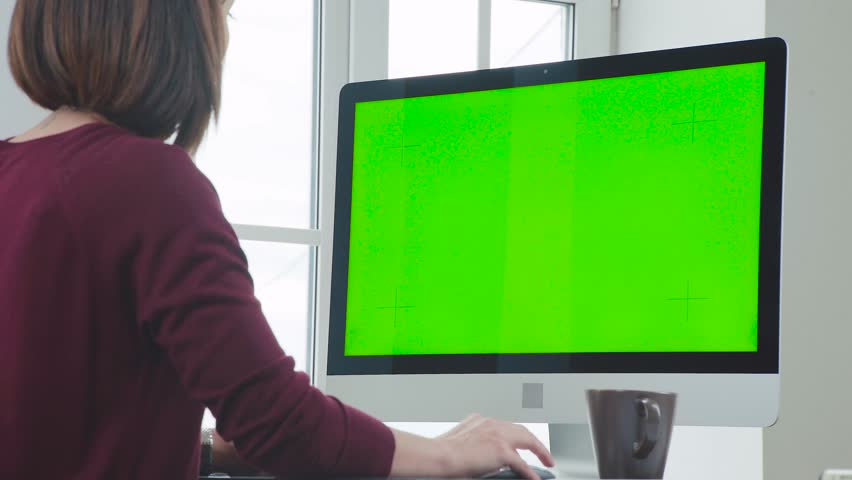Taken from the shoulder of a young girl sitting in front of a monitor. Woman is working in the office in front of a computer. Back of a woman with a short haircut, she sits in front of the monitor. | Shutterstock HD Video #1012336820