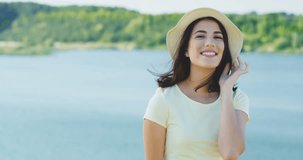 Portrait shot of the romantic attractive young woman in the hat posing nice and smile near the lake. Outdoor.