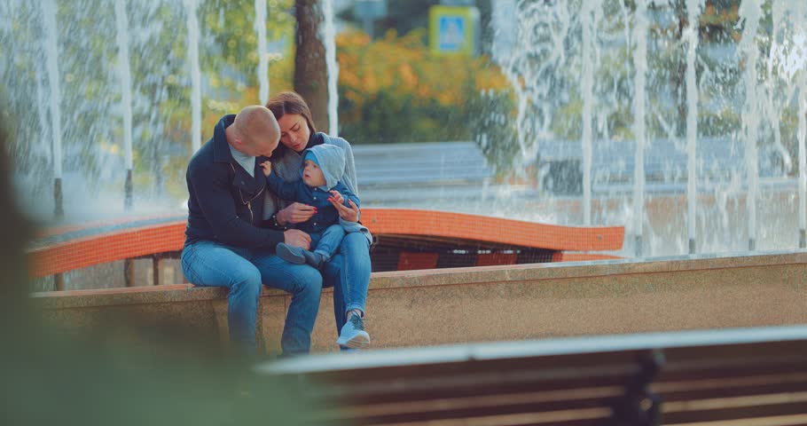 Happy family sitting by the fountain in the park