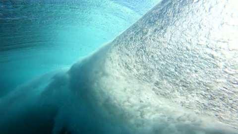 Blue surfing wave surface and underwater spinning vortex view